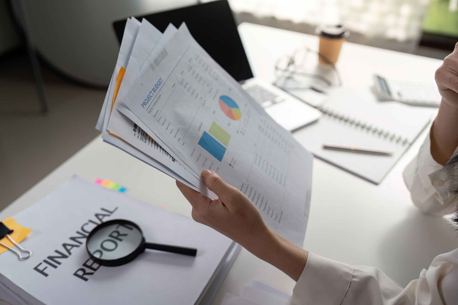 Individual reviewing financial reports and data analysis in a modern workspace.